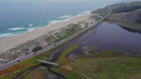 aerial drone view of cars driving in fog on pacific coast highway by san gregorio beach in california, usa