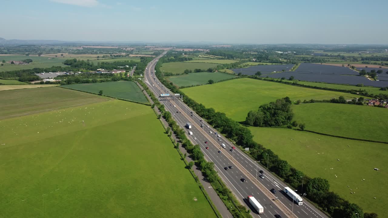 Aerial view of a highway with traffic surrounded by green fields and solar panels