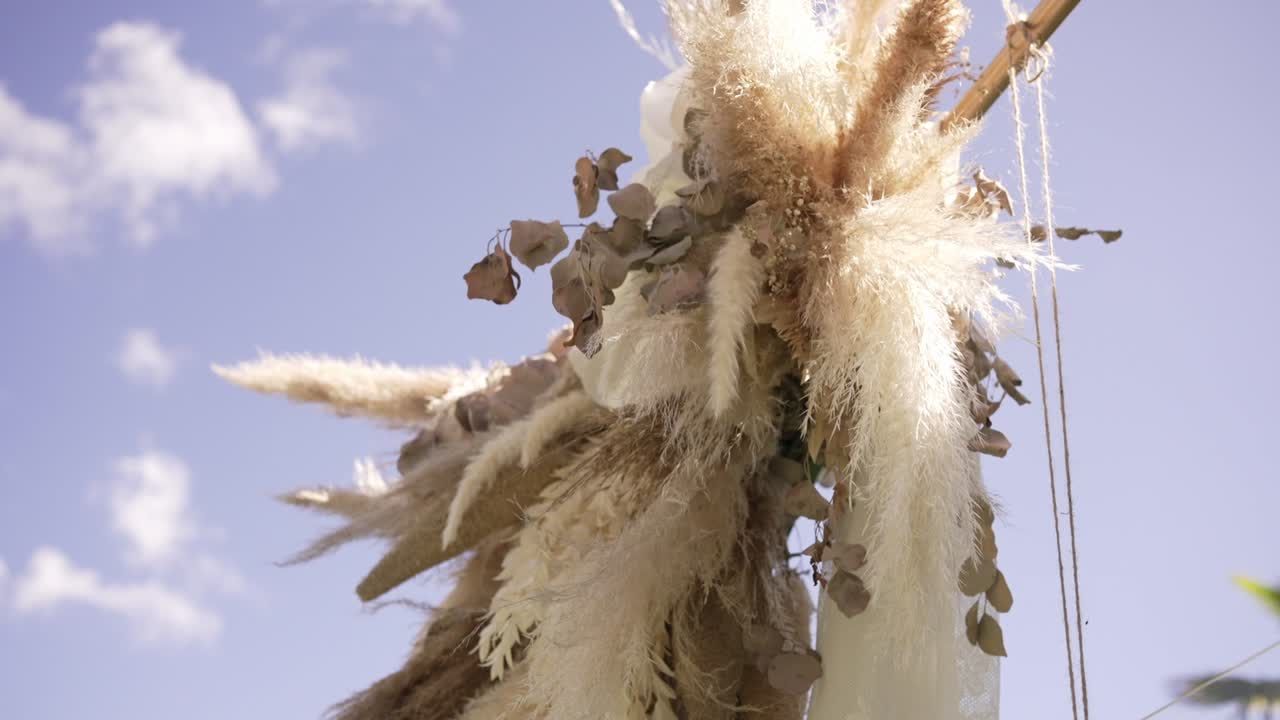 Boho style floral arrangement with pampas grass and dried leaves against a clear sky