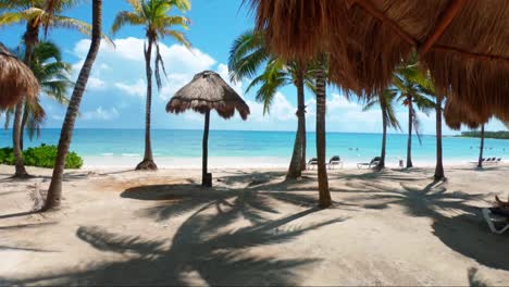 Gorgeous-shot-walking-through-a-tropical-beach-with-white-sand,-palm-trees,-and-turquoise-water-on-the-beautiful-Playa-del-Carmen-in-Riviera-Maya,-Mexico-near-Cancun-on-a-sunny-summer-day-on-vacation