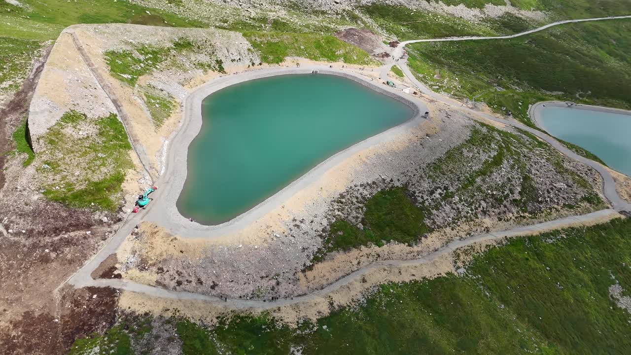 Aerial top down of idyllic Schafbergsee Lake in Gargellen, Austria. Path for hiker in Austrian mountains during sunny day in summer.