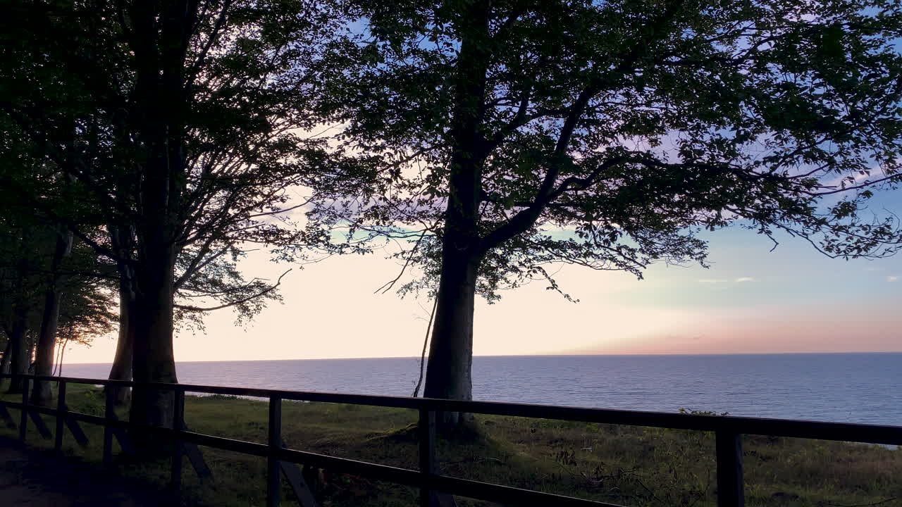 폴란드 자스트르제비아 고라 마을의 삼림 공원 근처 잔잔한 바다 위로 아름다운 파란색과 분홍색의 일몰