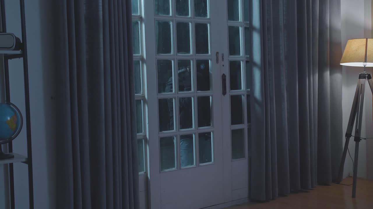 어두운 밤에 밖에서 서 있는 동안 집 안을 바라보는 불을 들고 있는 도