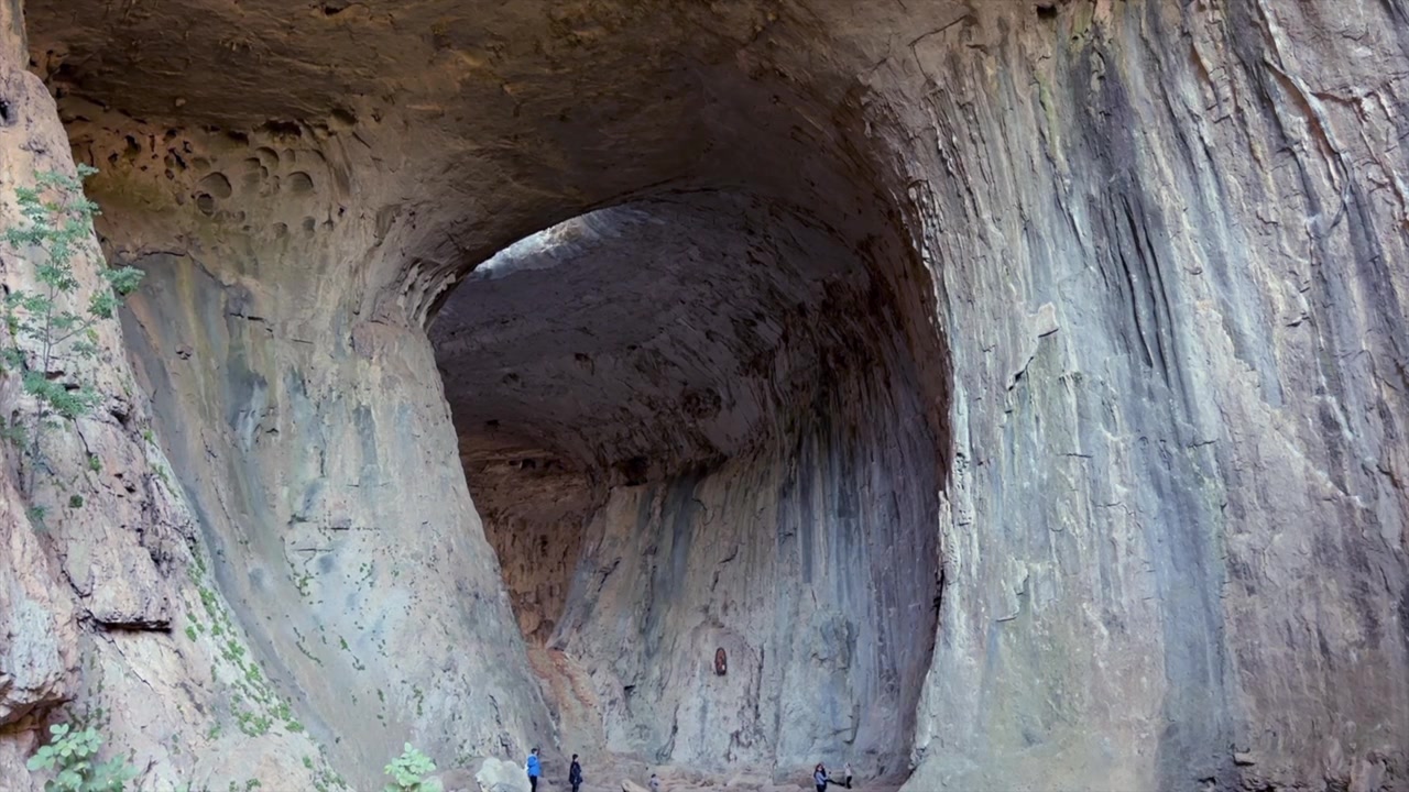 Vista magnífica de Prohodna, uma caverna cárstica localizada no centro-norte da Bulgária. Os pequenos visitantes explorando o interior oferecem uma perspectiva sobre o tamanho da caverna