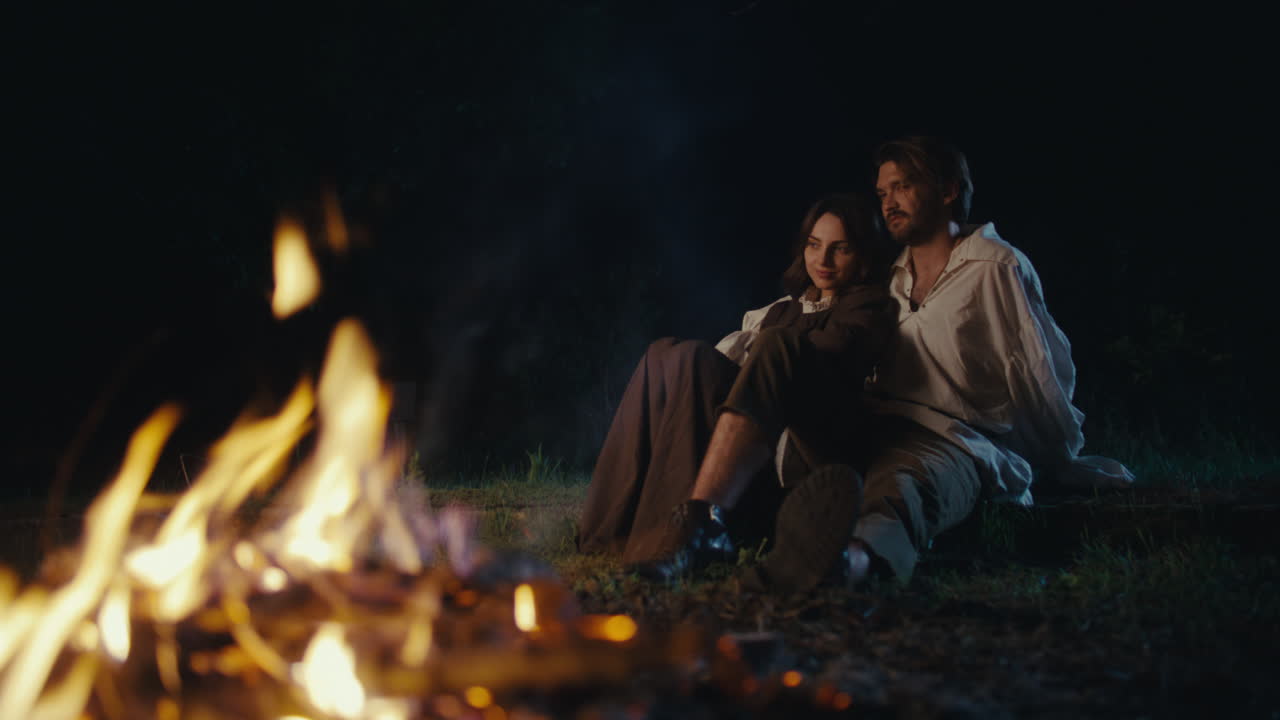 Couple Sitting by a Campfire at Night