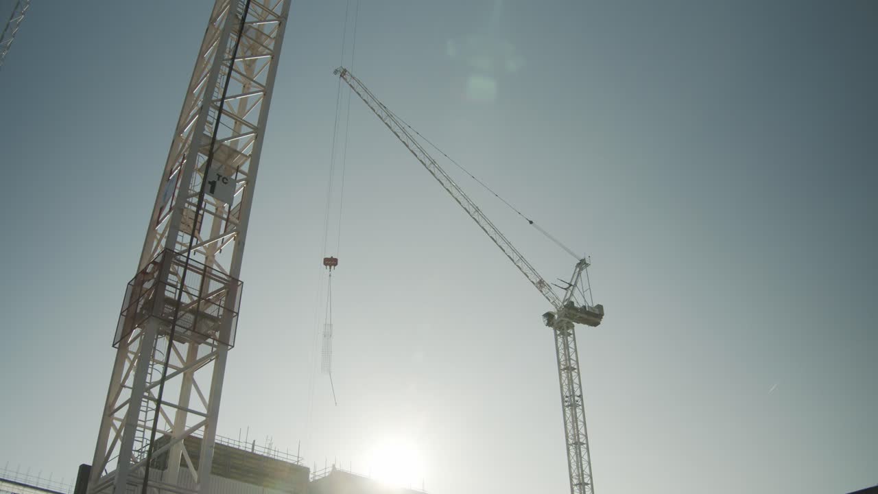 Two cranes are seen against a sunny sky