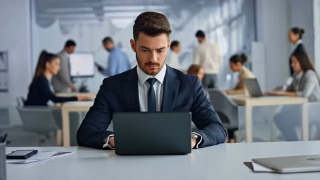 professional man working on laptop in a busy office environment