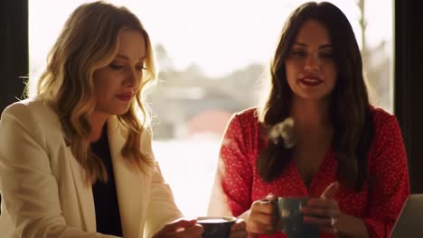two friends share a warm conversation while enjoying coffee at a charming cafe. sunlight streams through the windows, creating a relaxed atmosphere for them to connect.