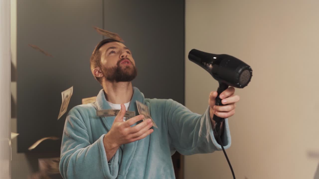 un hombre alegre sopla billetes de dinero con un secador de pelo