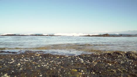 waves coming over a lava rock wave break and brushing against another formation