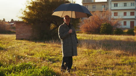 man standing still under the sun rays with an open umbrella
