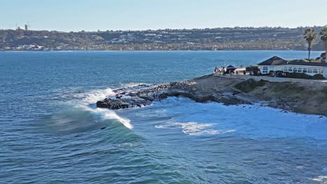 Drone-shot-of-waves-crashing-over-rocks-with-Sea-Lions-playing-in-surf-showing-horizonline-during-King-Tide-in-La-Jolla,-California