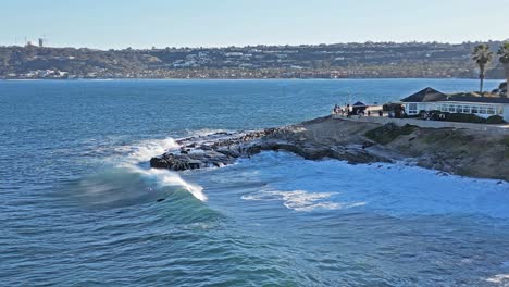 Toma-De-Drones-De-Olas-Rompiendo-Sobre-Rocas-Con-Leones-Marinos-Jugando-En-El-Surf-Mostrando-El-Horizonte-Durante-La-Marea-Real-En-La-Jolla,-California