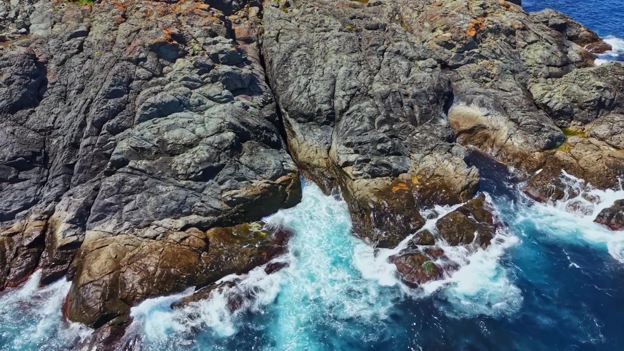 Onde che si infrangono contro la costa rocciosa in una zona costiera durante il giorno vicino all'oceano.