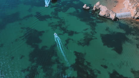 Boat-in-the-ocean-during-the-summer-in-Praia-Dona-Ana-in-the-Algarve-in-Portugal,-aerial-drone-view