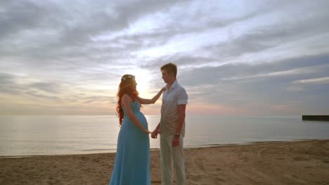 pregnant couple on beach at sunrise. man and woman on sea beach