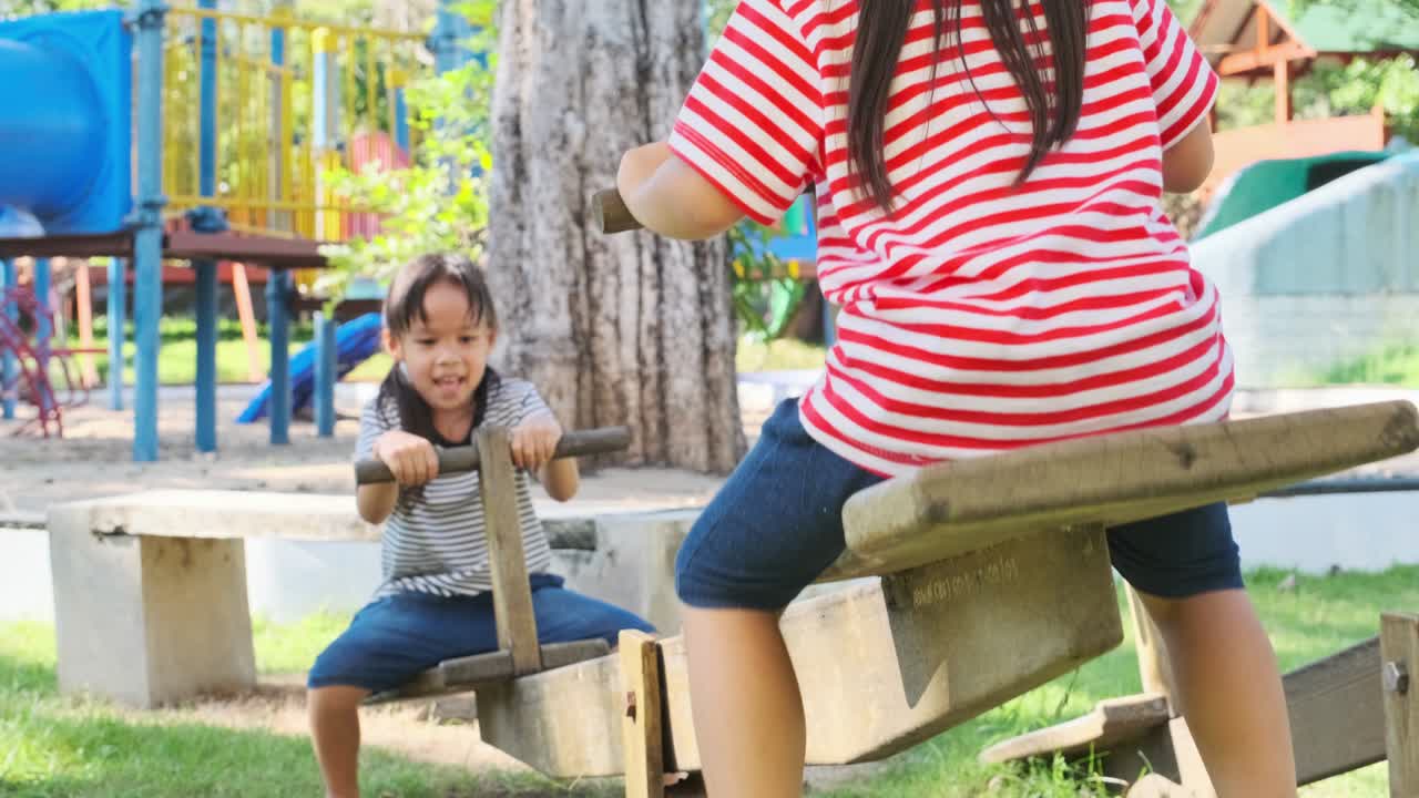hermanas pequeñas activas jugando en un columpio en el patio de recreo al aire libre. niñas felices sonriendo y riendo en el parque infantil. jugar es aprender en la infancia.