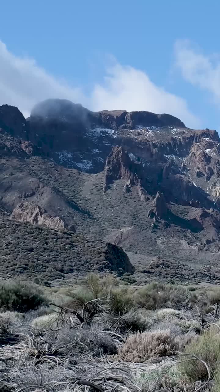 La telecamera si muove verso l'alto per rivelare un maestoso paesaggio montano roccioso