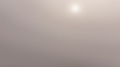 an aerial view reveals a residential area in weesen and the serene walensee lake as a drone passes through a foggy and misty layer. the tranquil lake and peaceful village emerge from the mist.