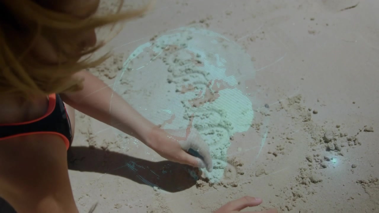 Video verticale: Bambino che preme il dito, disegnando una spirale nella sabbia, con un globo blu che si muove e guida il gioco tecnologico.