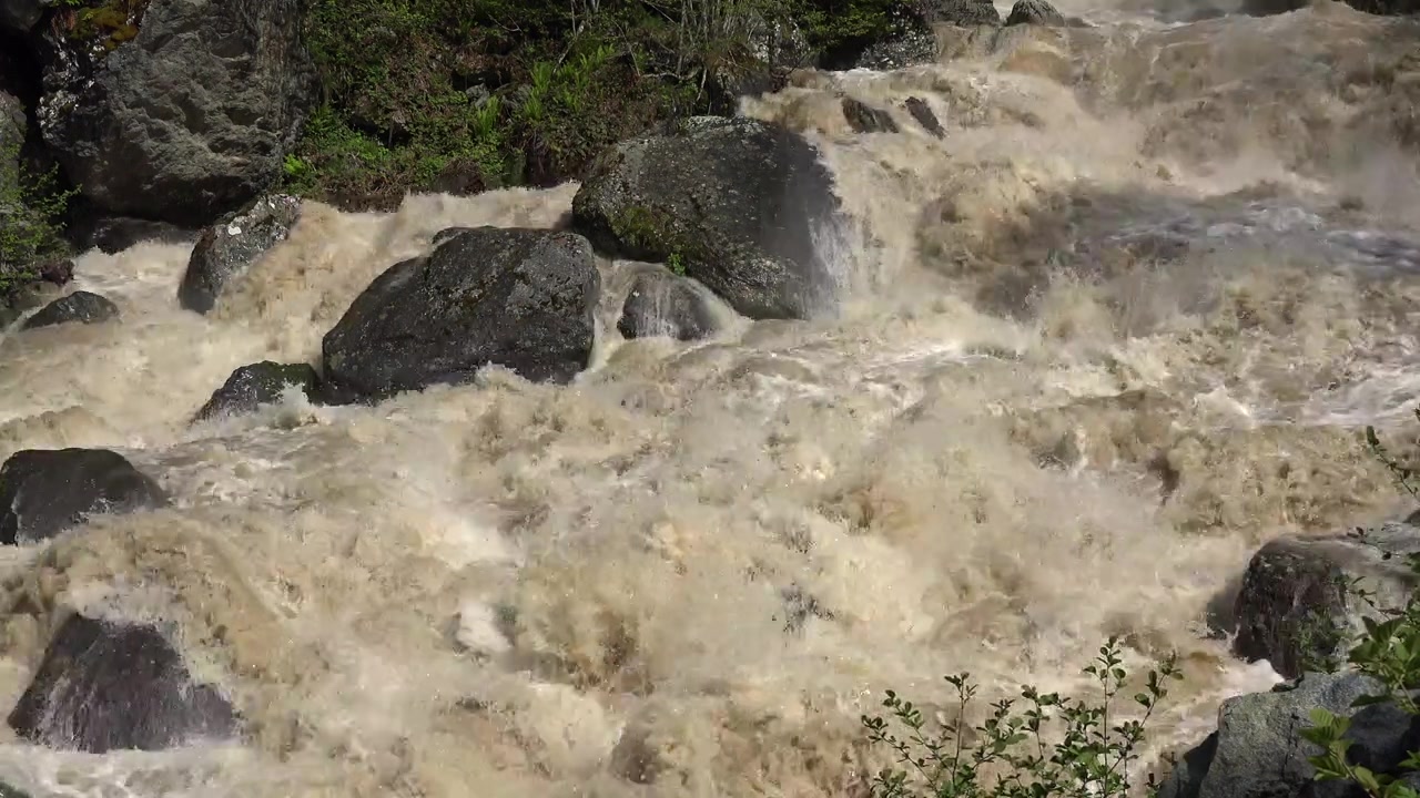 Acqua impetuosa e torbida di fiume che scorre sulle rocce