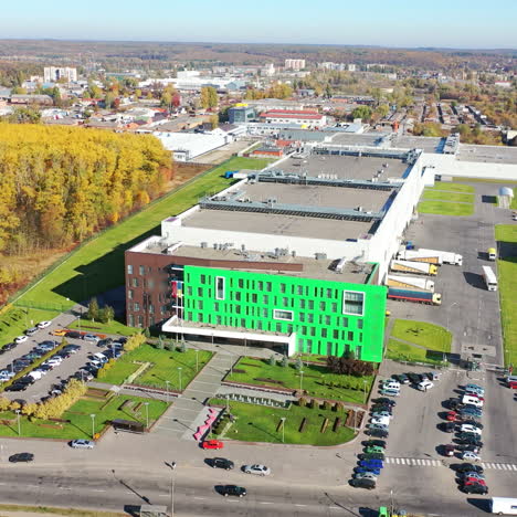 große fabrik aus der vogelperspektive. äußeres einer modernen anlage mit vielen parkplätzen. zeitgenössischer komplex im städtischen hintergrund. luftansicht.
