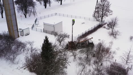 Professional-lineman-working-on-electricity-pole-to-restore-power-outage-in-winter,-aerial