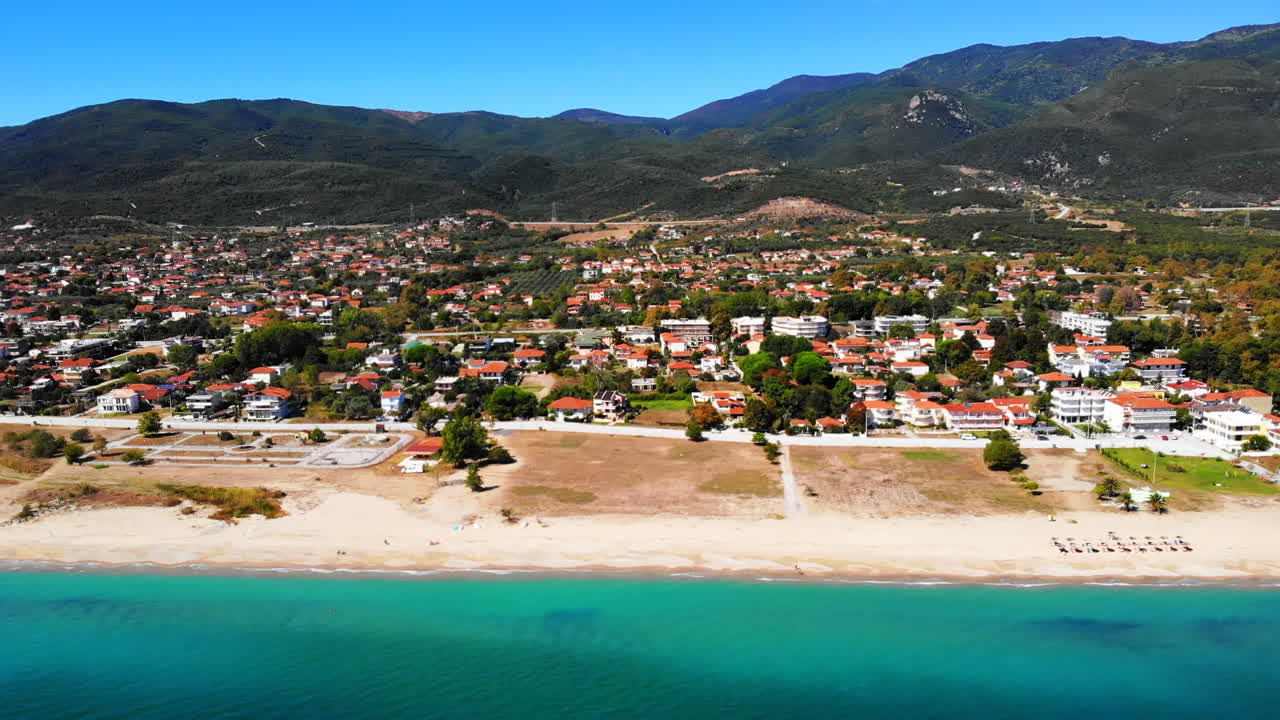 View of Asprovalta from the drone. Buildings and greenery, long beach along the town. Blue water of the Aegean sea. Green hills on the background. Greece