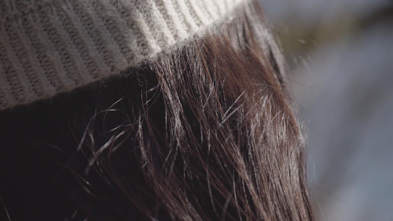 Cashmere winter hat on a woman with averted gaze in winter time sunny day.