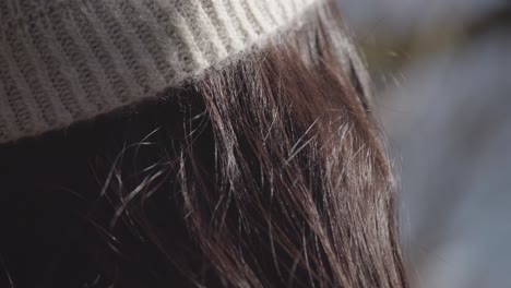 cashmere winter hat on a woman with averted gaze in winter time sunny day.