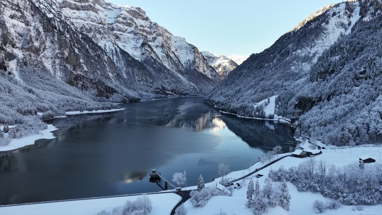 Talvinen alppilaakso ja jäinen järvenranta Klöntalerseessä Sveitsissä