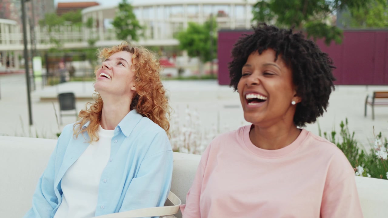 Two Happy Young Women Talking and Laughing Outdoors