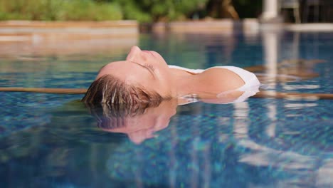 una joven relajada disfrutando del día de verano mientras toma el sol en la piscina