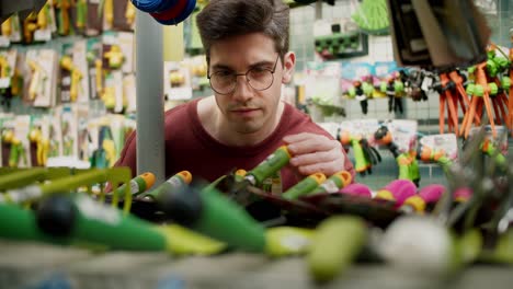 equipos de jardinería de compras con un joven en suéter marrón y gafas