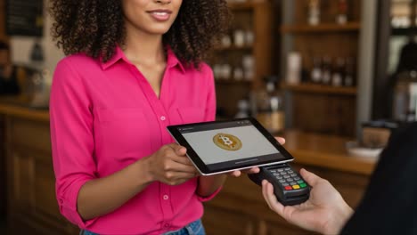 a smiling woman at a café engaging in a modern bitcoin transaction using a tablet to make a payment with a contactless reader