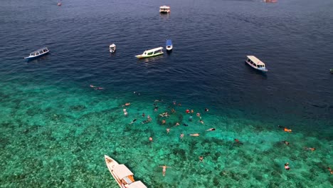 Indonesische-Ausflugsboote-Ankerten-Im-Türkisfarbenen-Wasser-Am-Schnorchelplatz-Der-Gili-Statuen,-Während-Menschen-Tauchen-Und-Schwimmen-–-Luftaufnahme