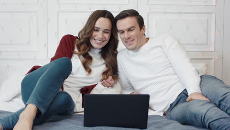 happy couple watching movie on computer at home together