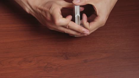 close-up of hands failing at shuffling a deck of cards on a table