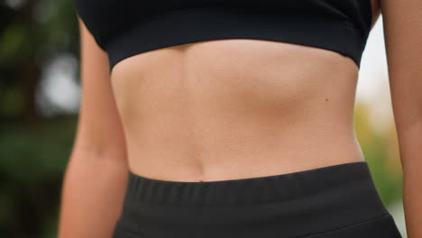 close-up view of a woman's stomach with goosebumps as she breathes in deeply, showing her physical response to a deep breath while wearing black workout gear, focusing on her midsection