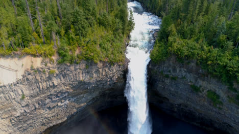 Beautiful-water-fall-through-forest-cliff-on-a-sunny-day-4k