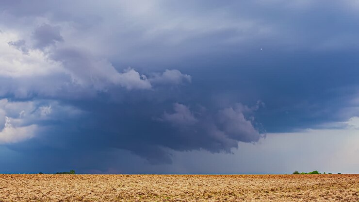 Timelapse Clouds Swirling and Forming Overing Latvia's Farmland Landscape Illuminated with Blue Light