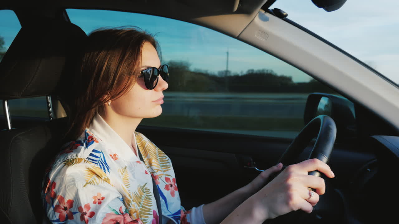 A Young Stylish Woman In Sunglasses Is Driving A Car
