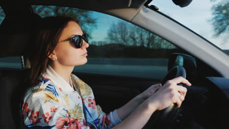 una mujer joven y elegante con gafas de sol conduce un coche