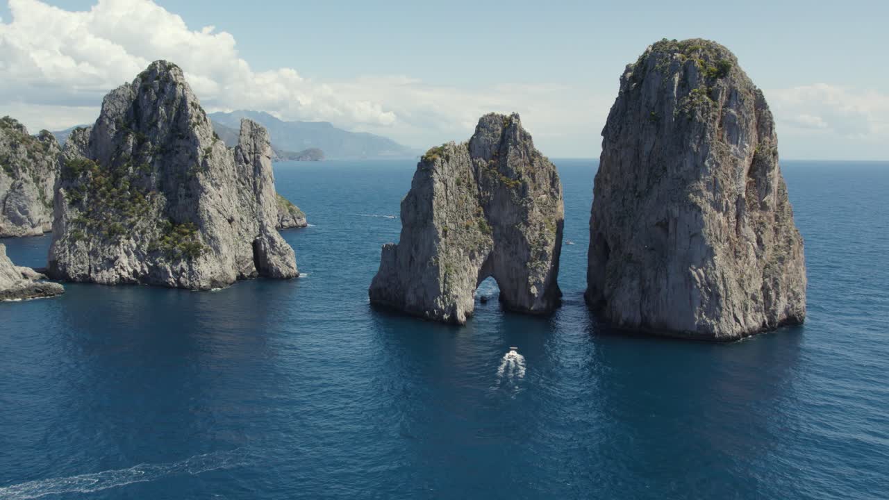 los barcos cruzan el arco natural de los farallones en capri