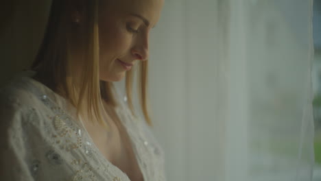 pregnant woman embracing her belly by the window