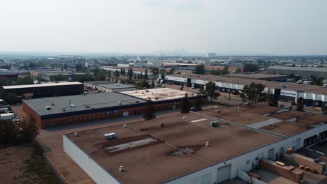 Fliegende-Drohne-über-Industriegebiet-In-Richtung-Calgary-Downtown-An-Einem-Dunstigen-Sommertag