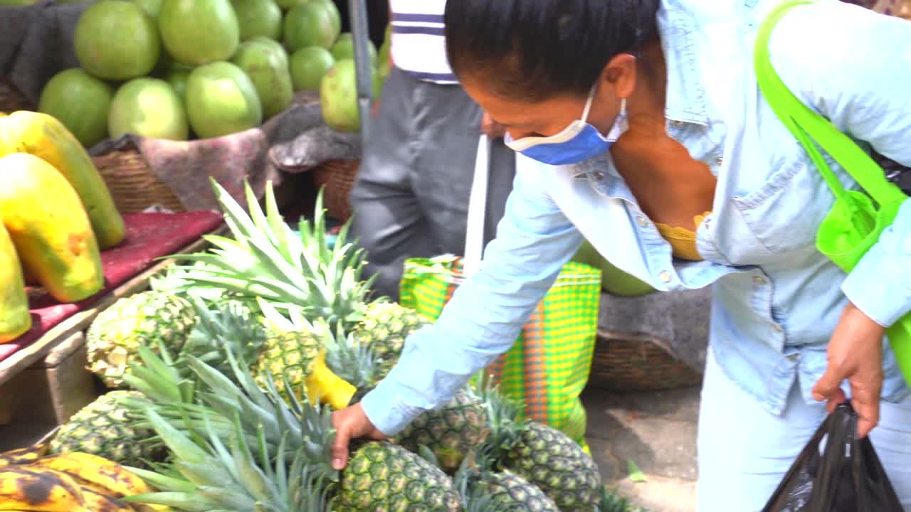 mujer hispana comprando fruta en america latina