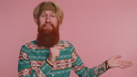 a man with a red beard and a green shirt smiles and points with his thumb