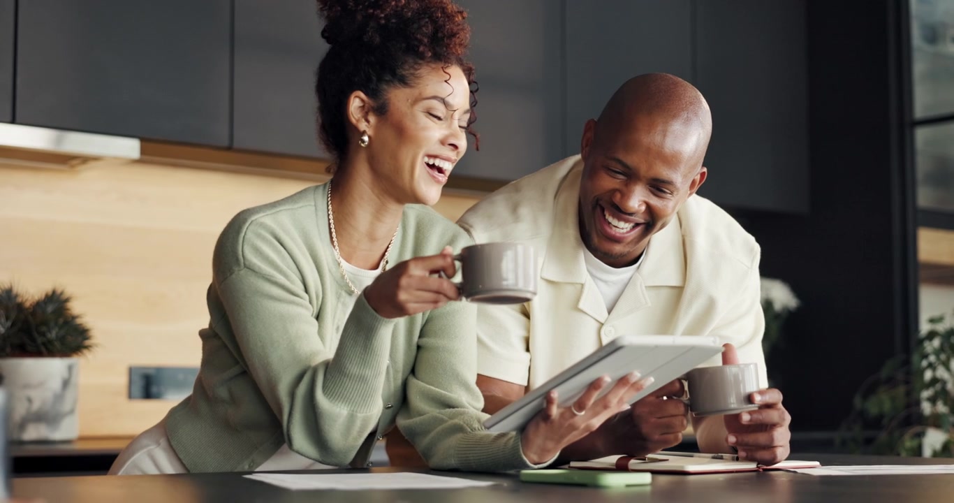 Coppia felice che beve caffè e usa un tablet in una cucina moderna