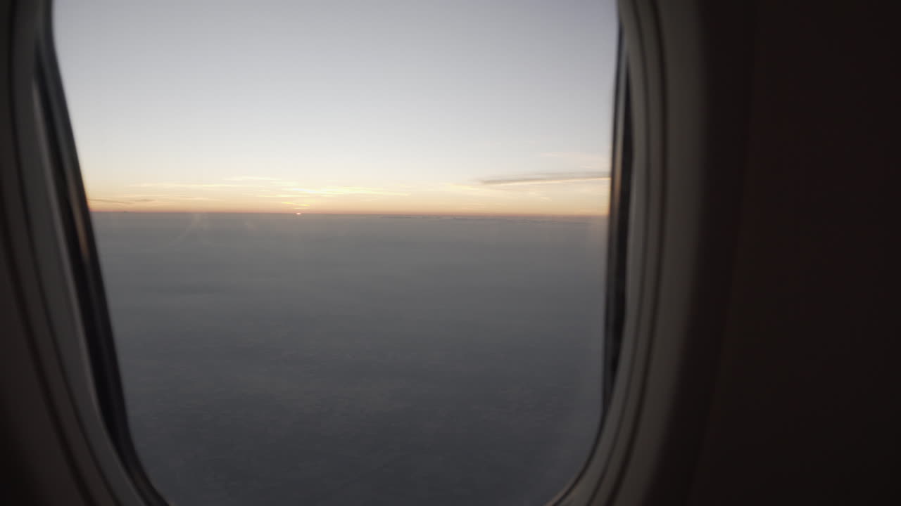 4K truck slide shot to the left and right of a plane window revealing a beautiful view of the sunrise or sunset outside with a  colorful sky.